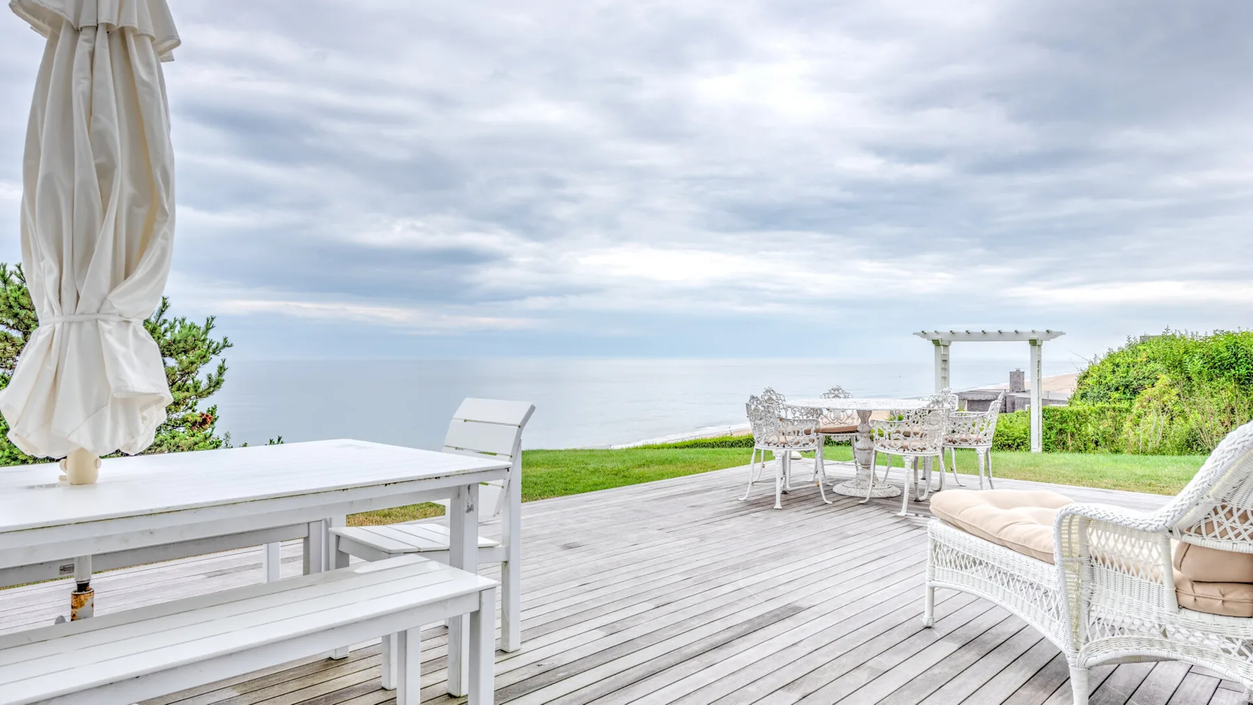An outdoor deck overlooks the water, with a dining table and lounge seating.