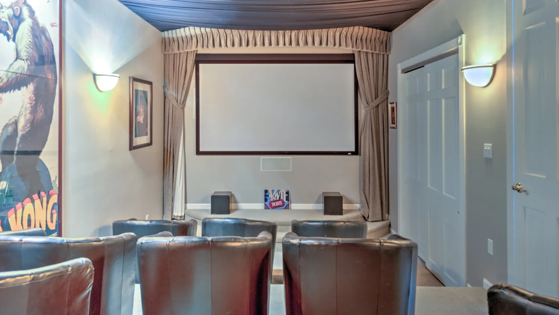 A small media room has rows of seating facing a projection screen.