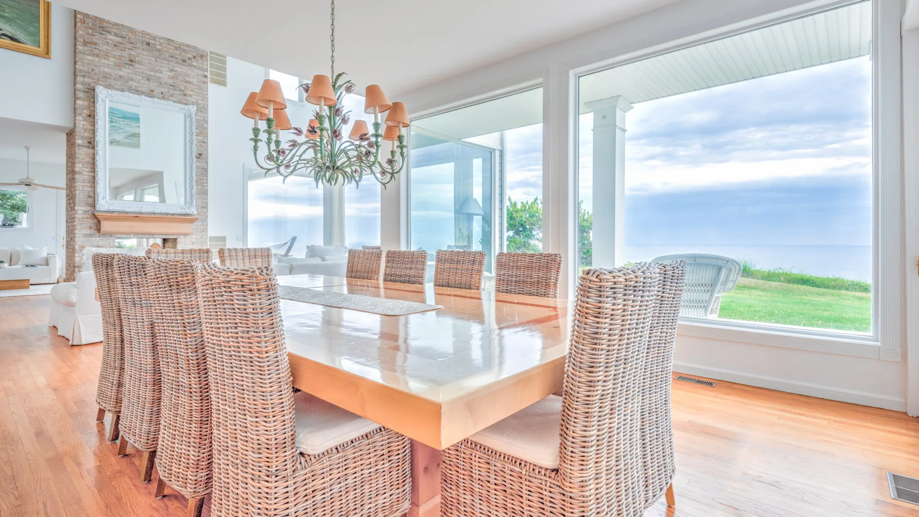 A bright dining area with a long table and woven seating beside large windows.