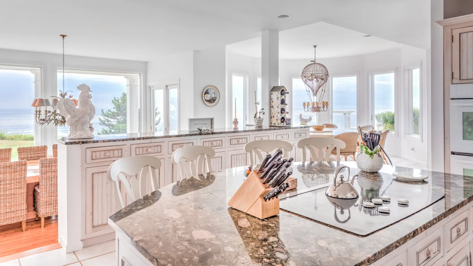 A bright kitchen with a large island, dining seating, and wide windows.