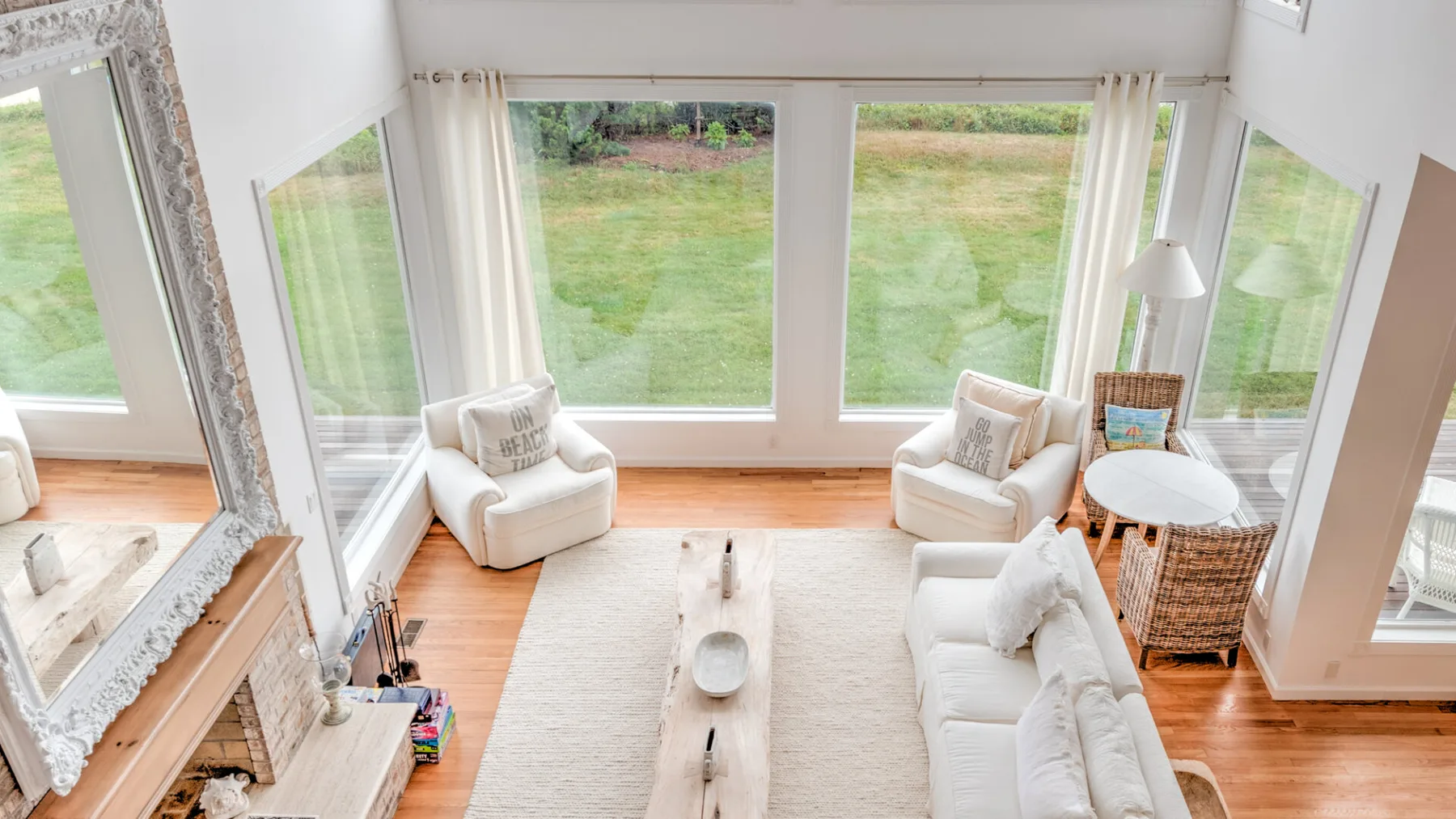 A bright living room with large windows overlooking a grassy garden.