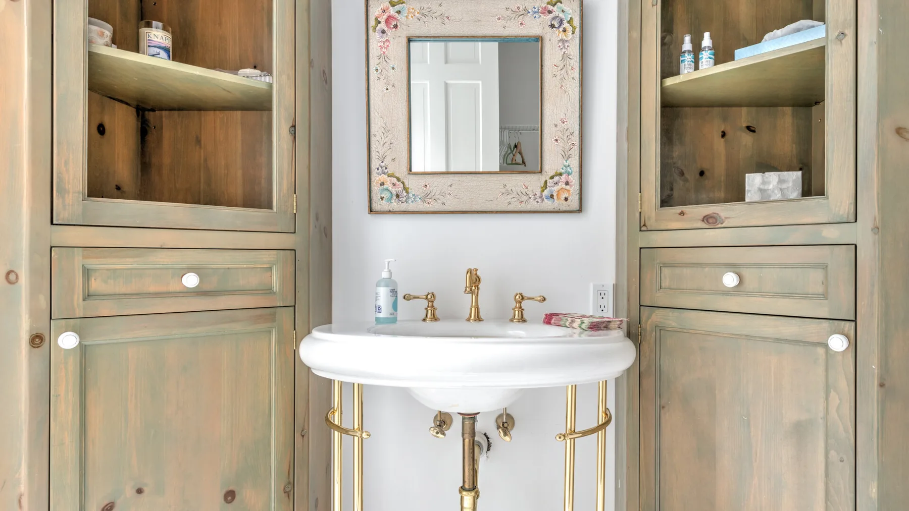 A bathroom vanity with a white basin and built-in wooden cabinets.