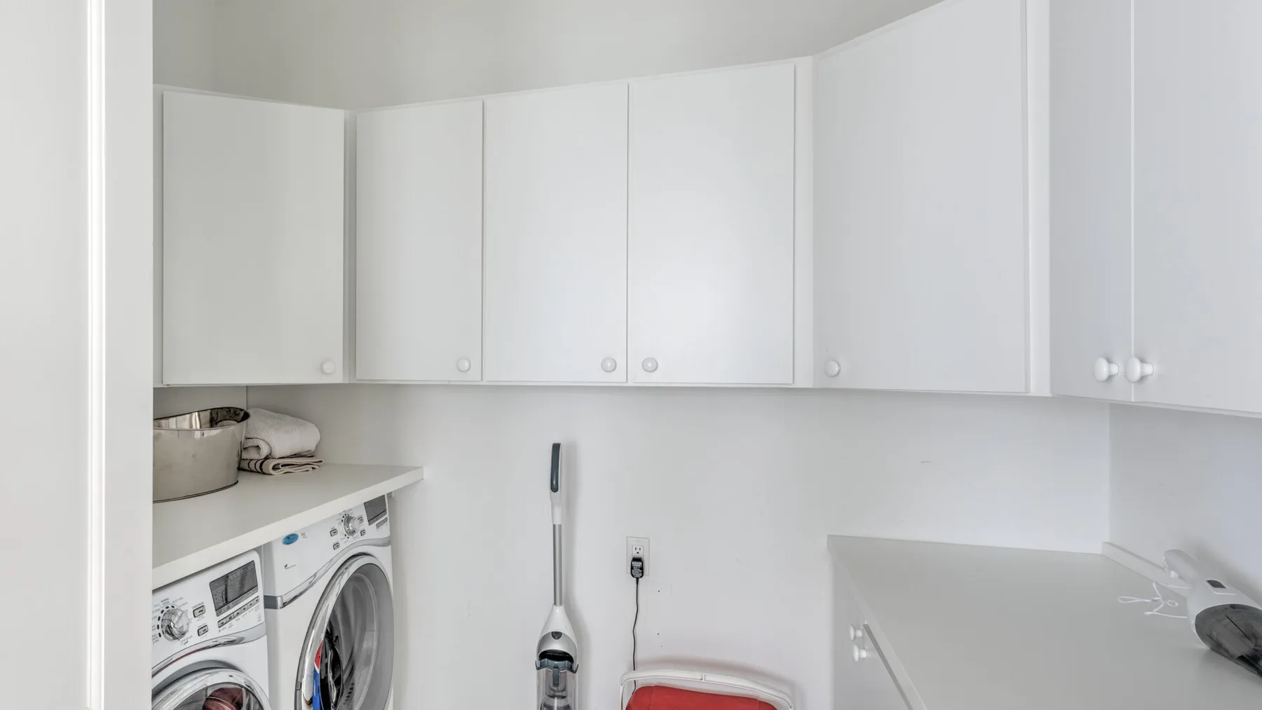 A compact laundry area with a washing machine beneath white cabinets.