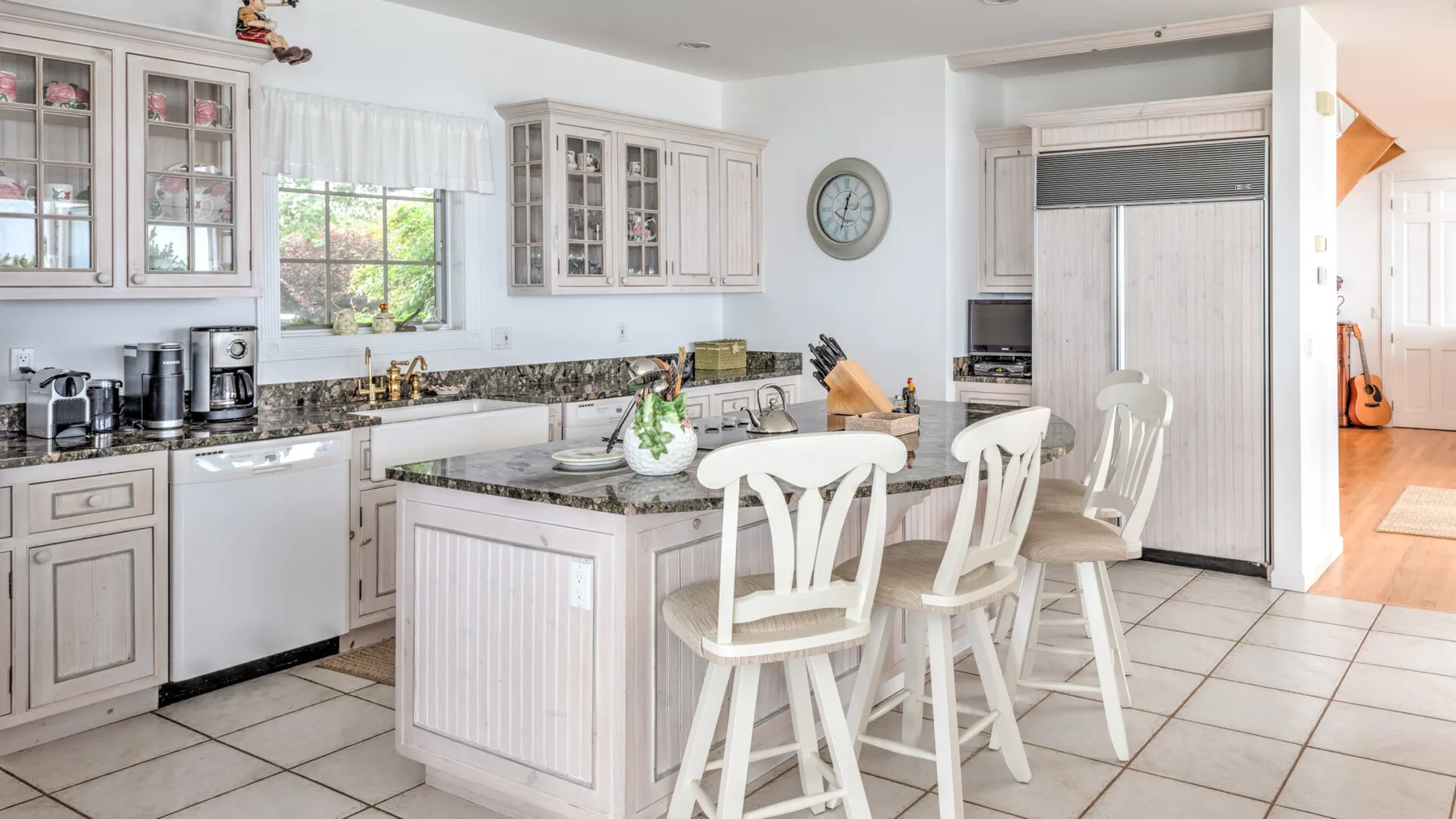 A bright kitchen with a central island and white seating.