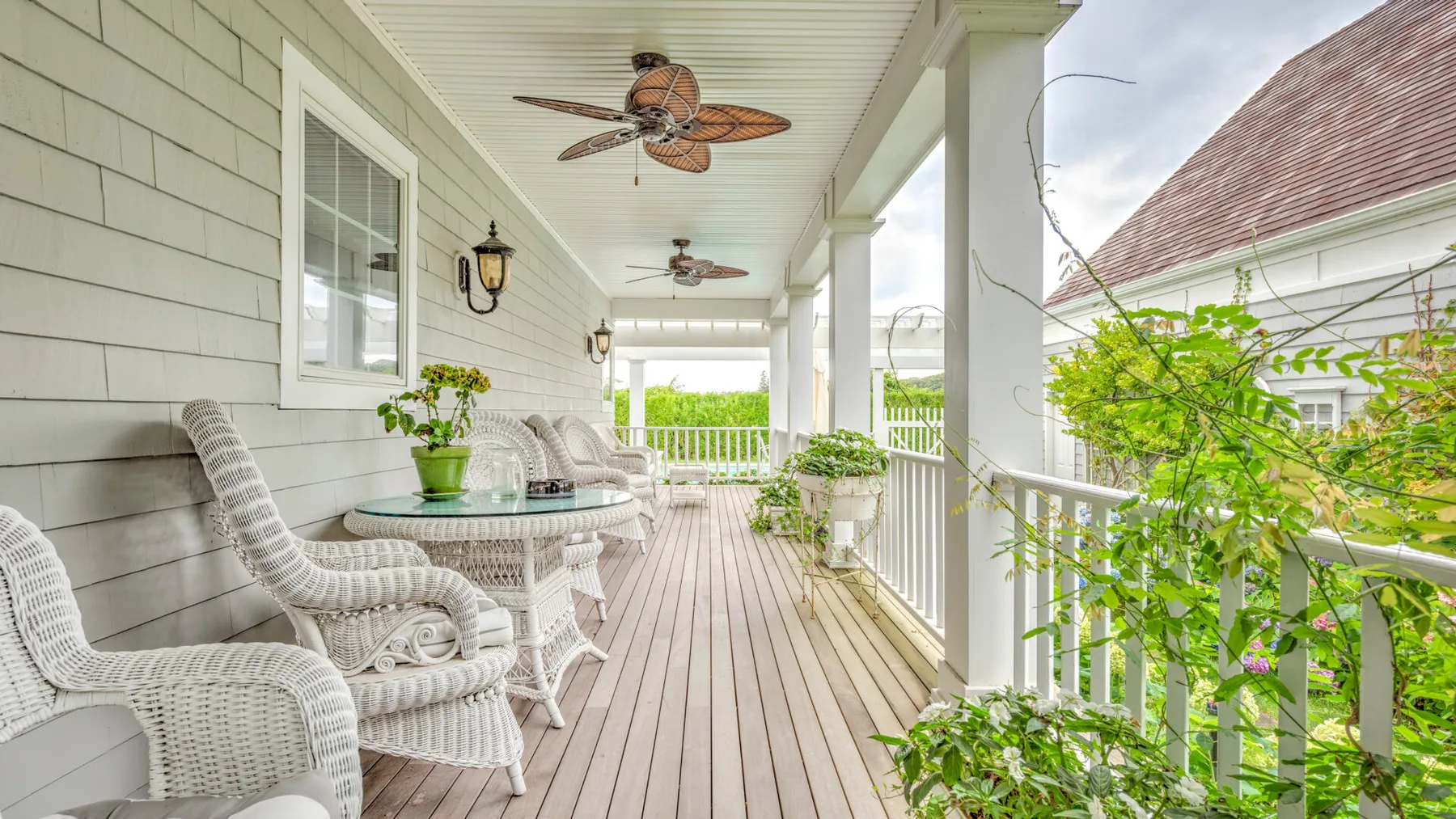A covered porch with wicker seating and a long wooden floor.