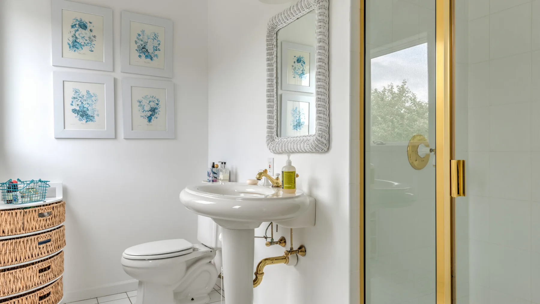 A bathroom with a pedestal sink, toilet, and glass shower door.