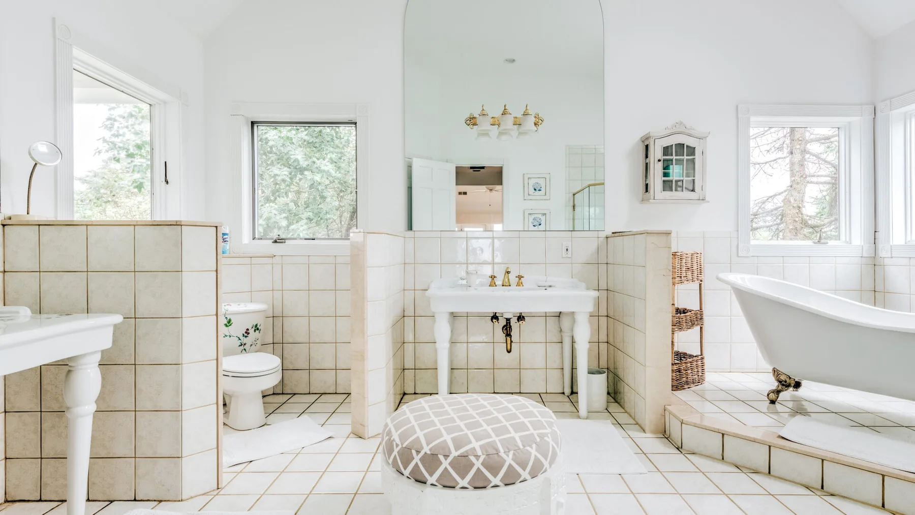 A bright bathroom with a central sink, a bathtub, and tiled surfaces.