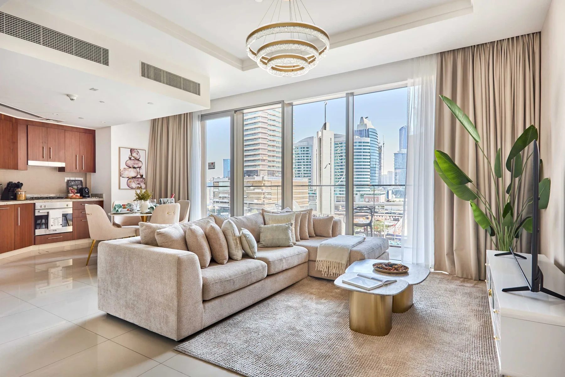 Una sala luminosa con un sofá y grandes ventanales con vistas a edificios de la ciudad.