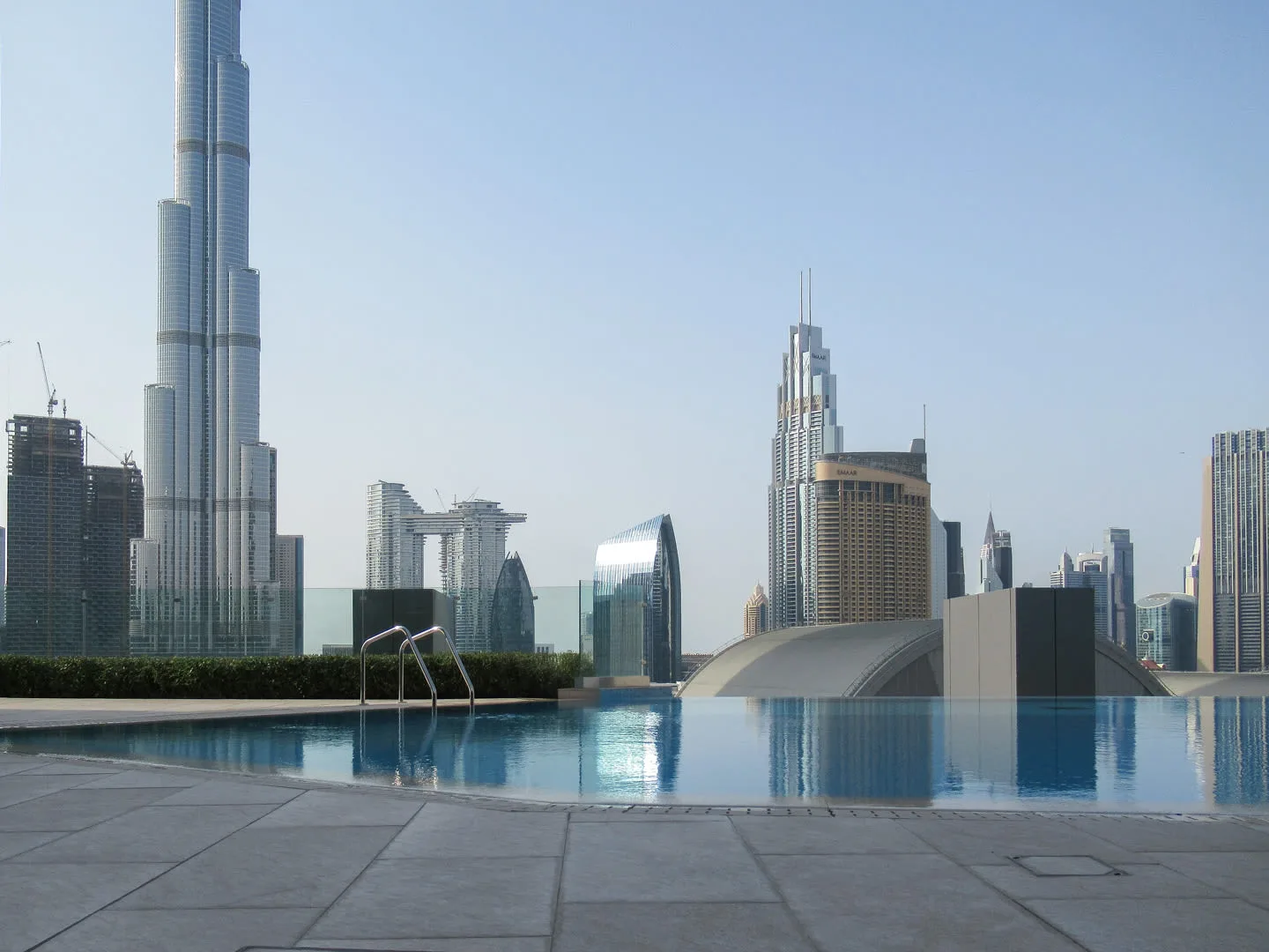 Una piscina en la azotea ofrece vistas del perfil urbano y una torre muy alta.