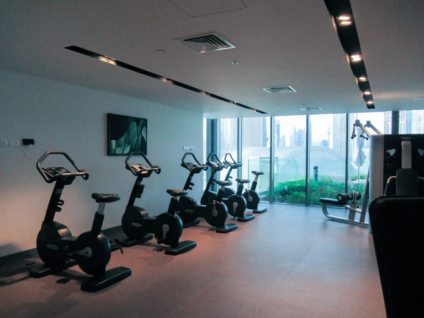 Una sala de ejercicio con bicicletas estáticas junto a grandes ventanales.