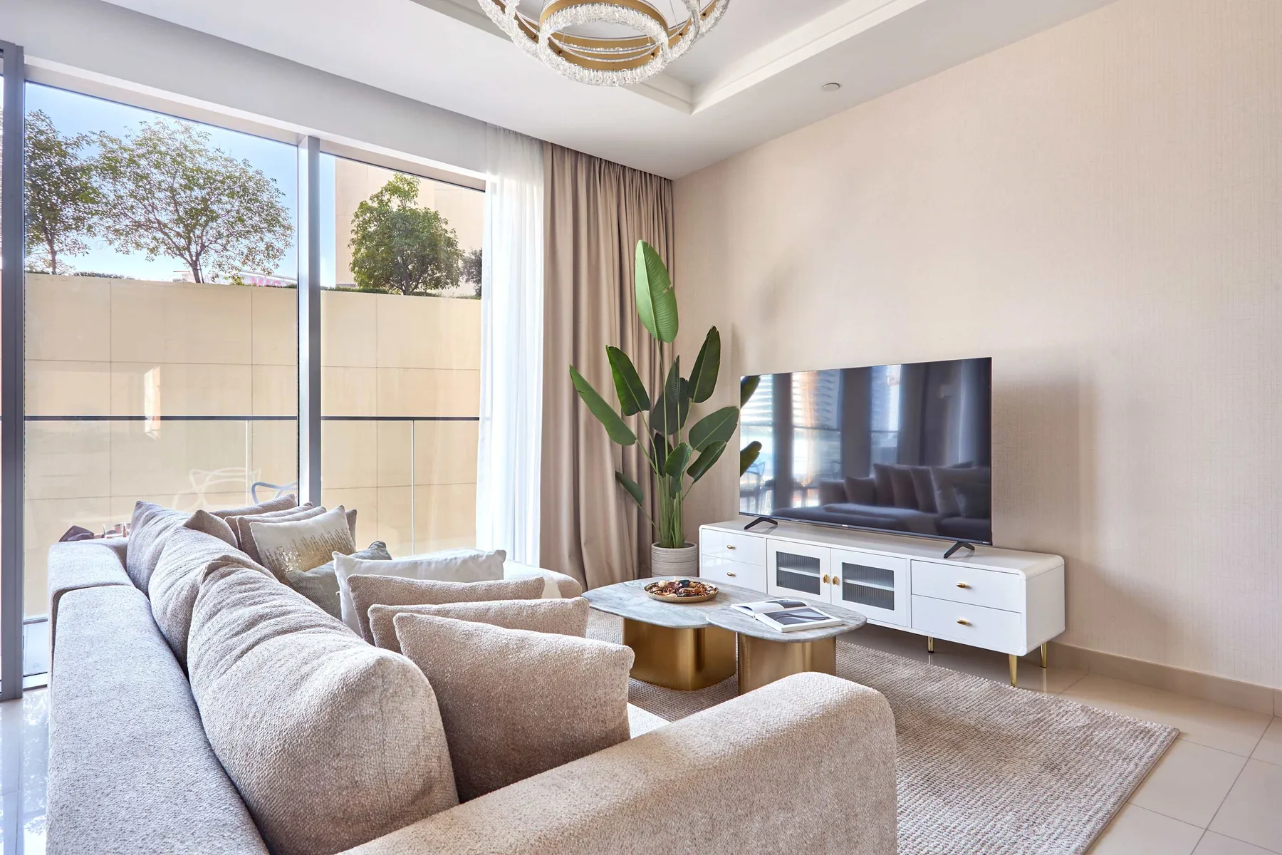 Una sala luminosa con asientos, un televisor y una ventana grande.