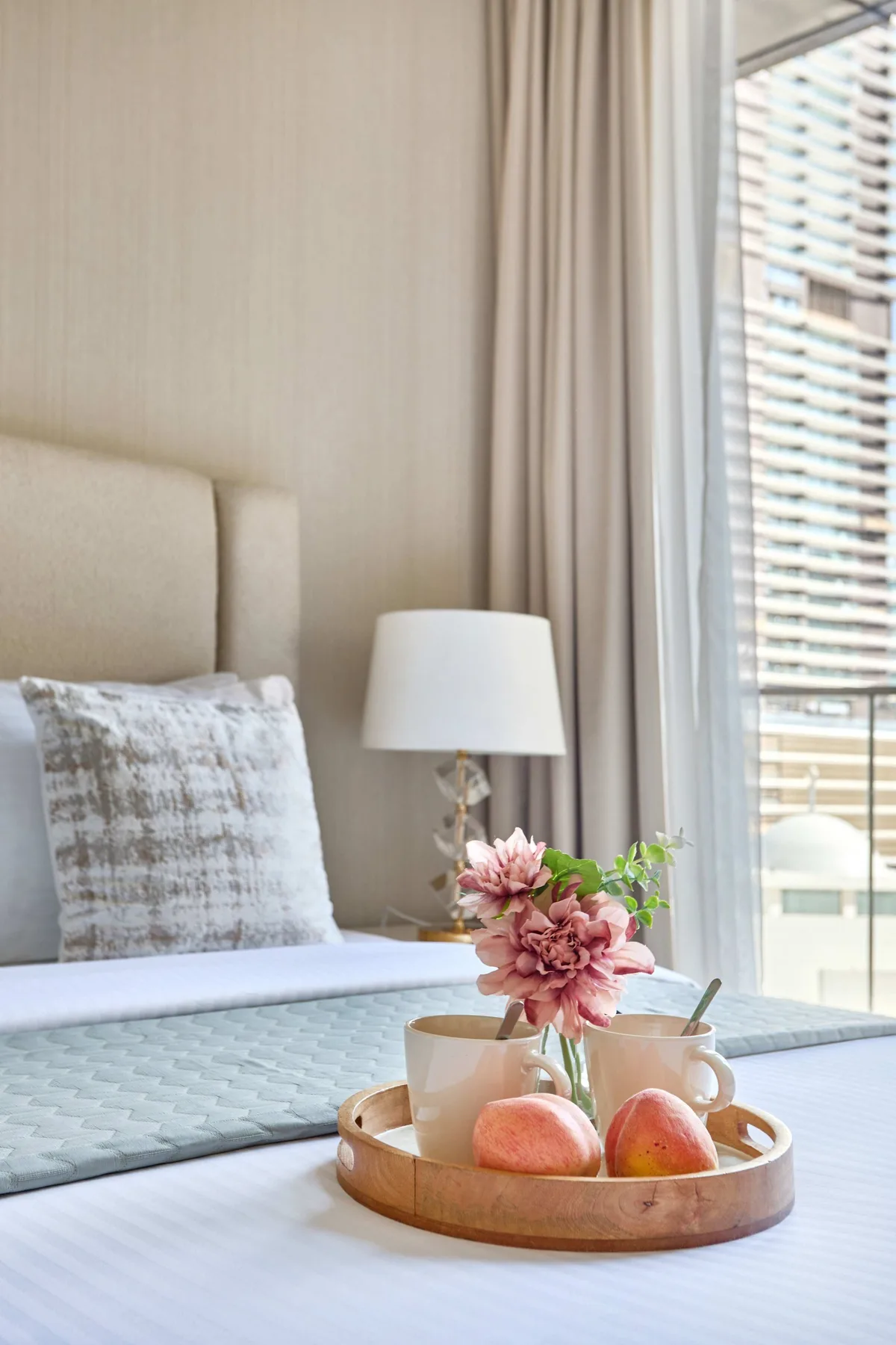 Dormitorio con flores y fruta en una bandeja sobre la cama.