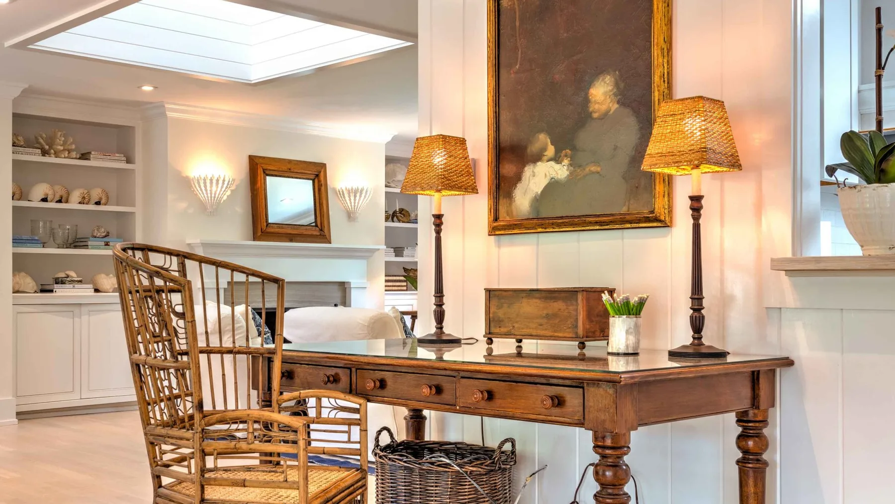 A bright sitting area with a wooden writing desk and wicker seating.
