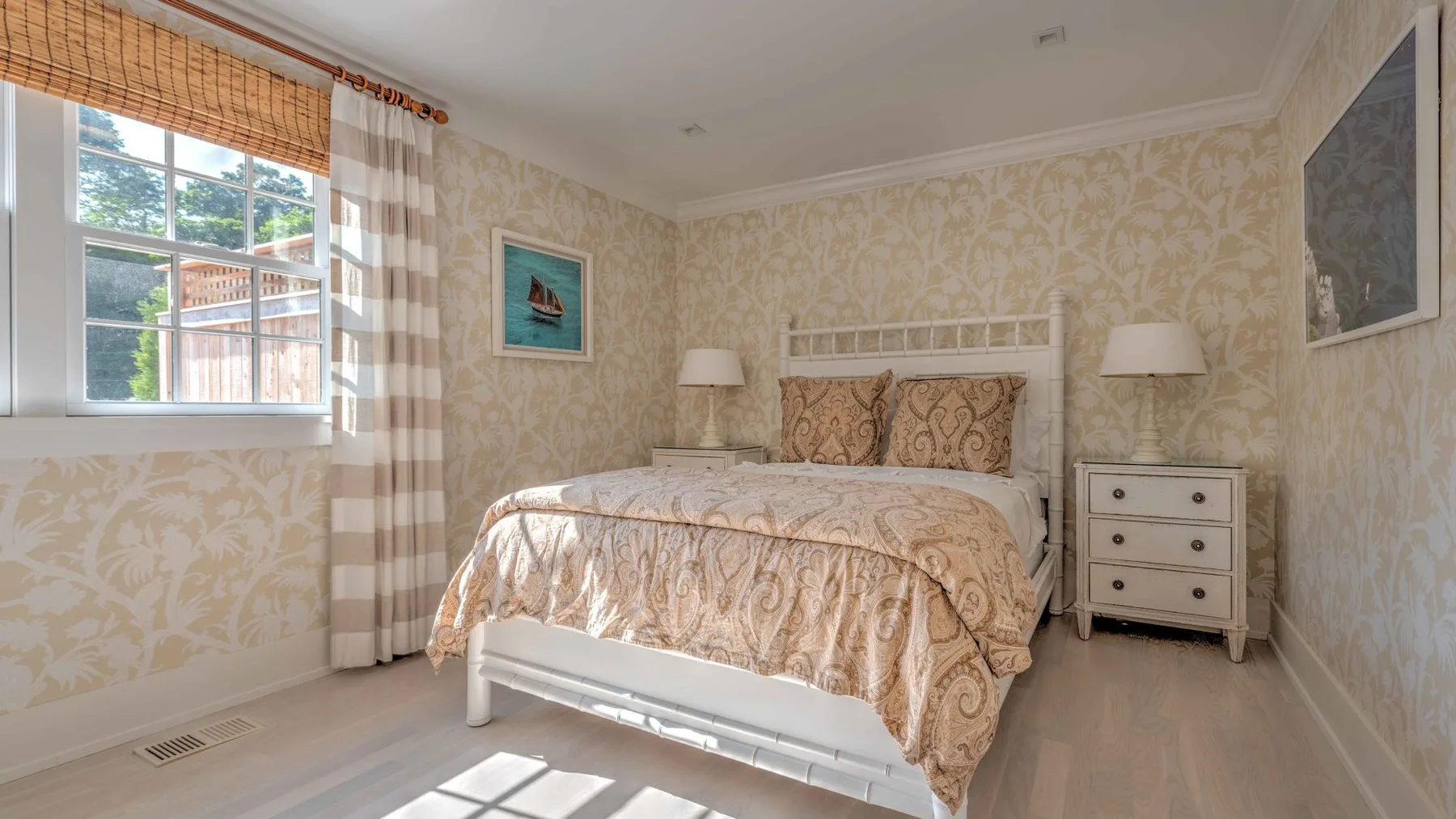 A bedroom with a bed, bedside tables, and a window.