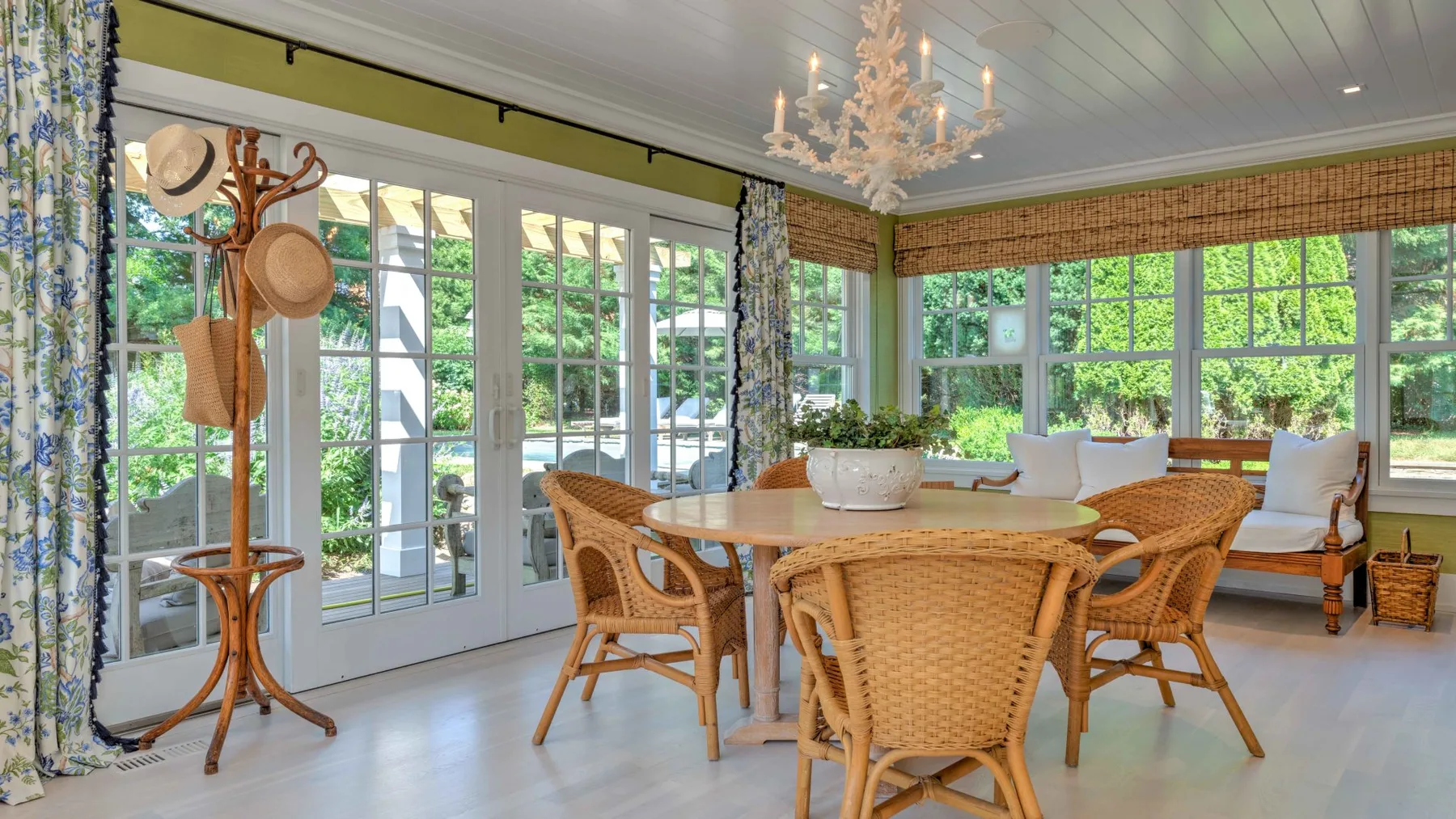 A bright dining room with a round table and woven seating beside large windows.