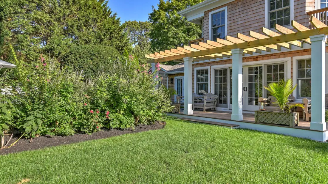 A landscaped garden and lawn beside a house with a wooden pergola.