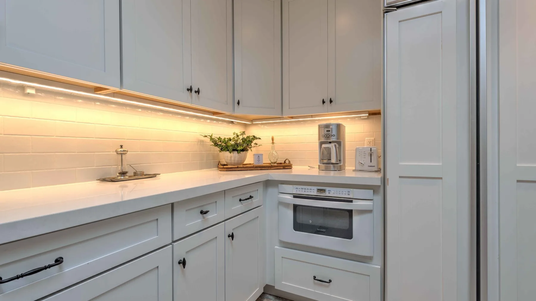 A bright kitchen with white cabinetry, a countertop, and built-in appliances.