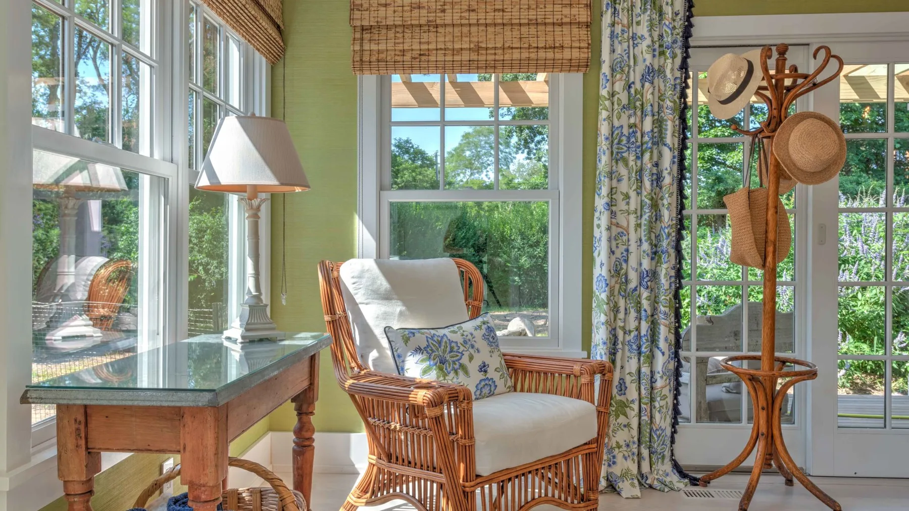 A bright sunroom with wicker seating beside large windows.