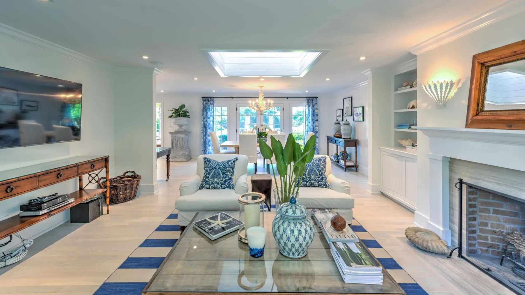 A bright living room with seating, a glass coffee table, and a fireplace.