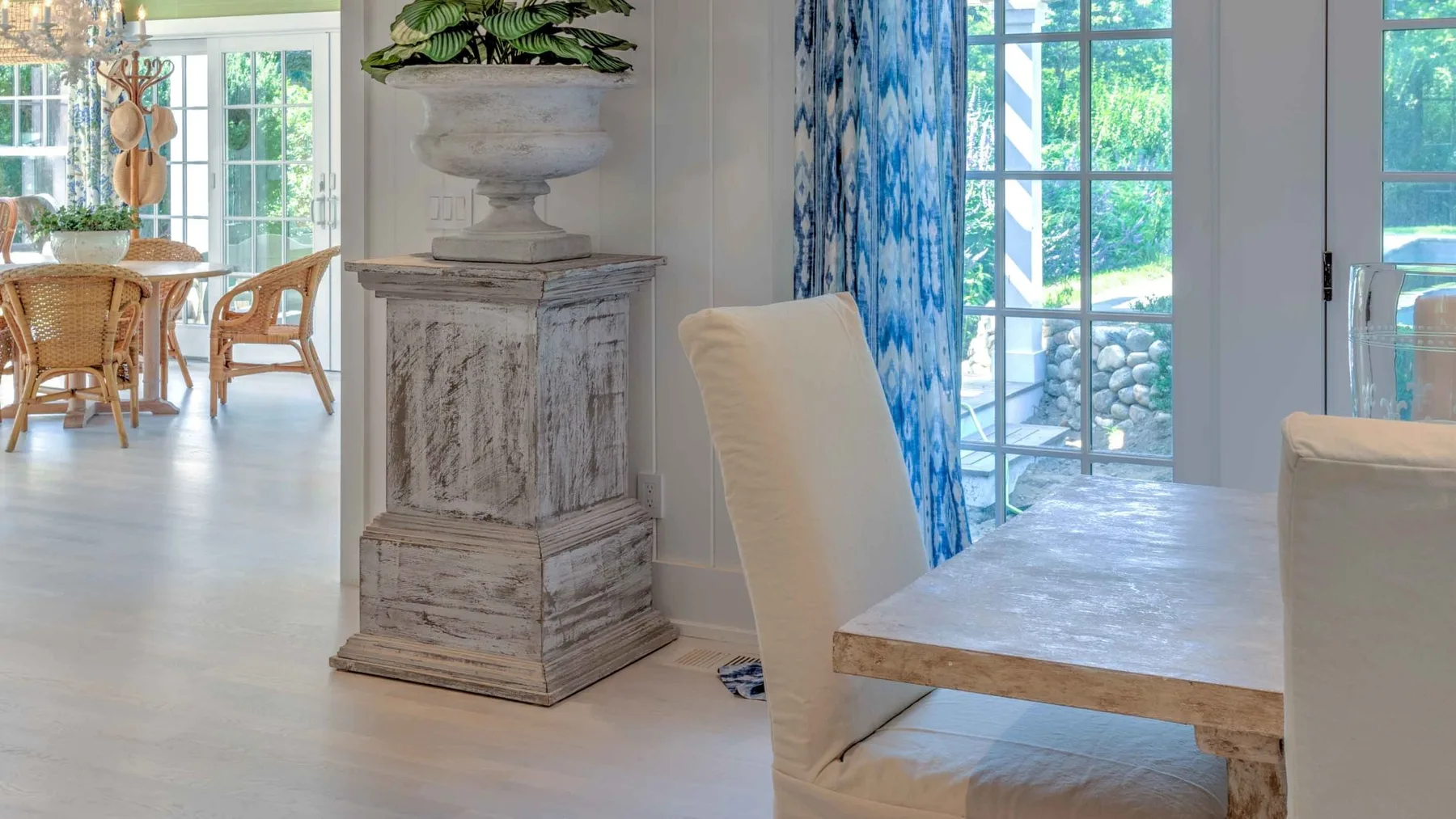 A bright dining area with a wooden table, upholstered seating, and large windows.