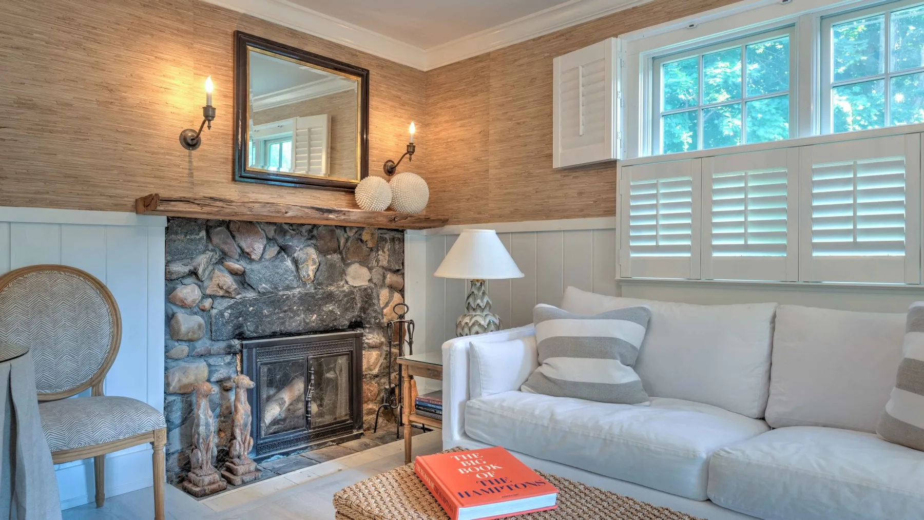 A living room with seating beside a stone fireplace and bright windows.
