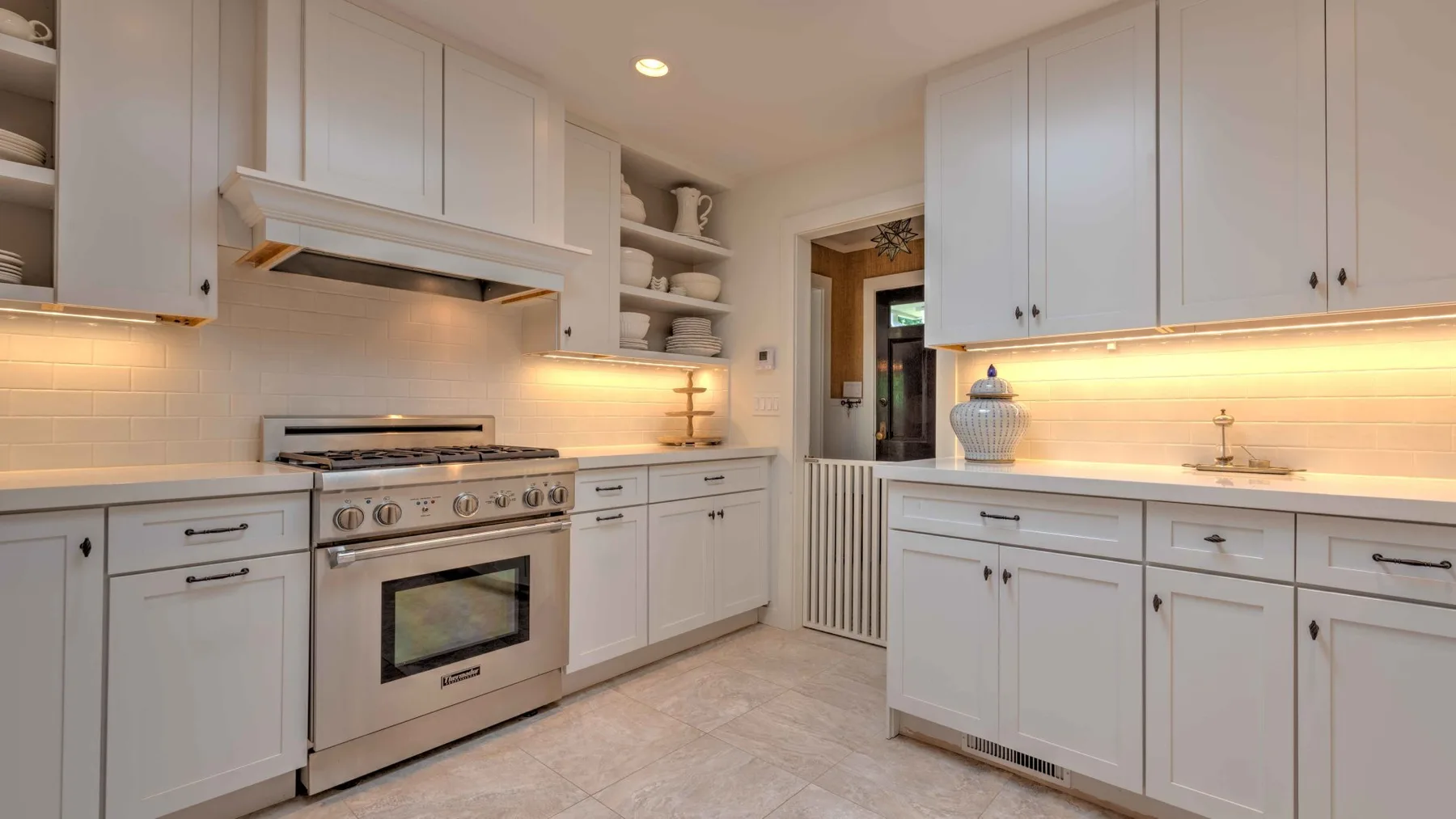 A bright kitchen with white cabinets, a stove, and light countertops.