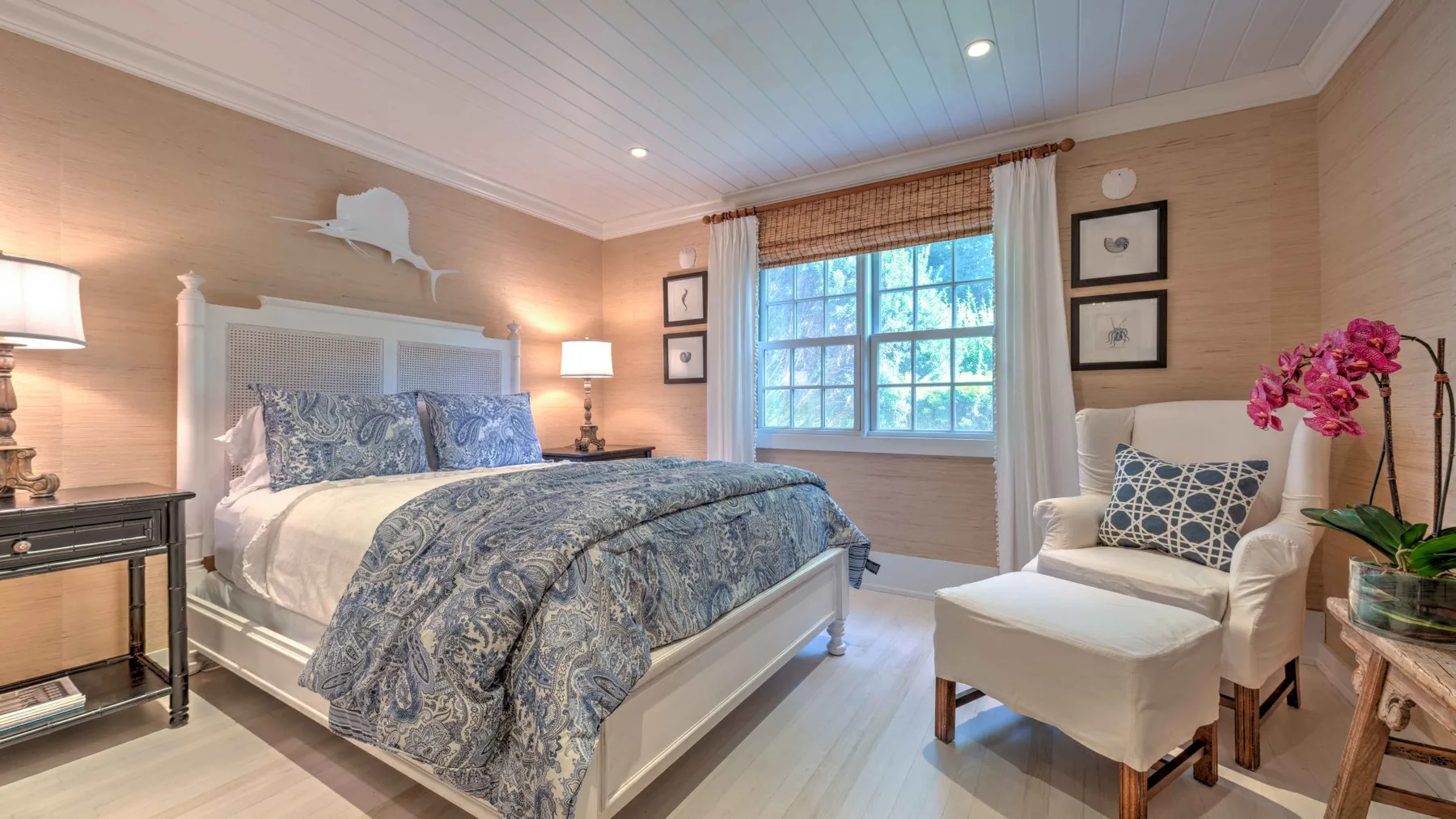 A bedroom with a large bed and a window beside a cushioned chair.
