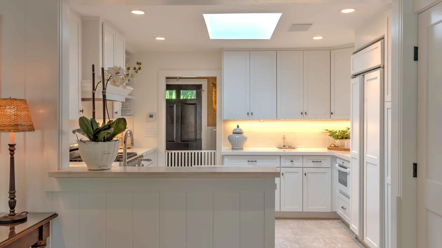 A bright kitchen with white cabinetry and a counter in the foreground.