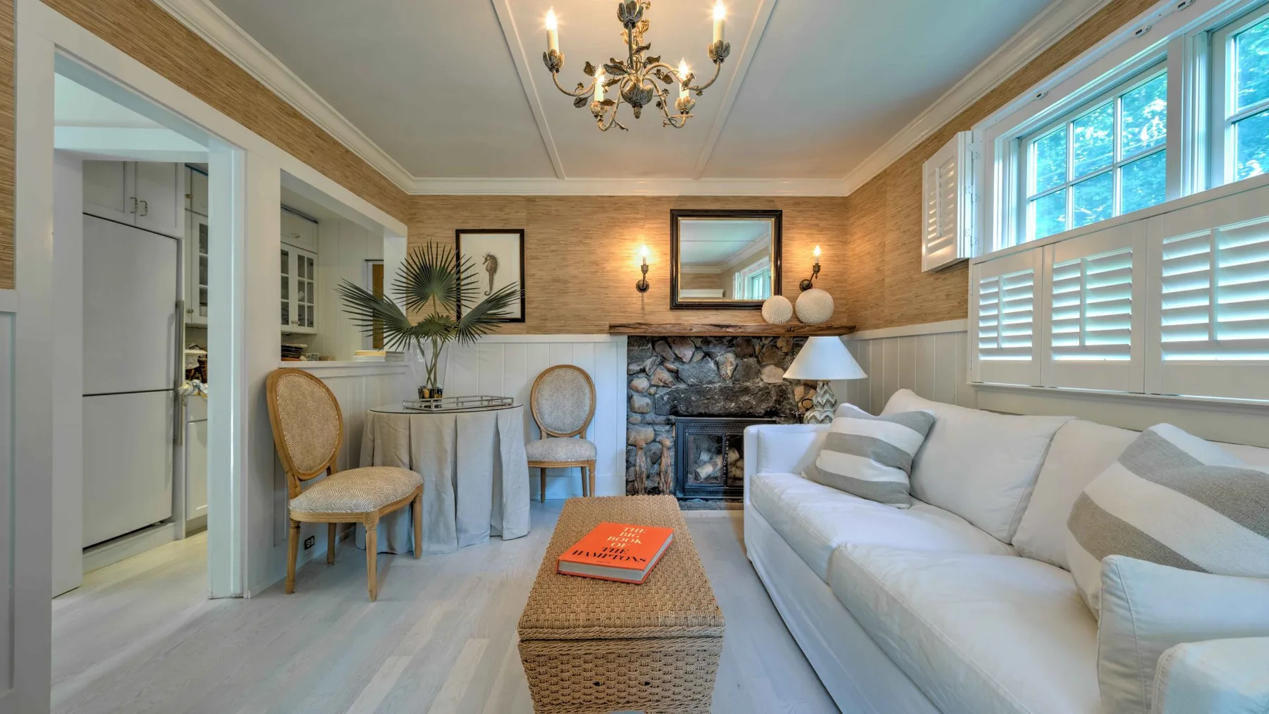 A bright living room with a white sofa, fireplace, and woven coffee table.