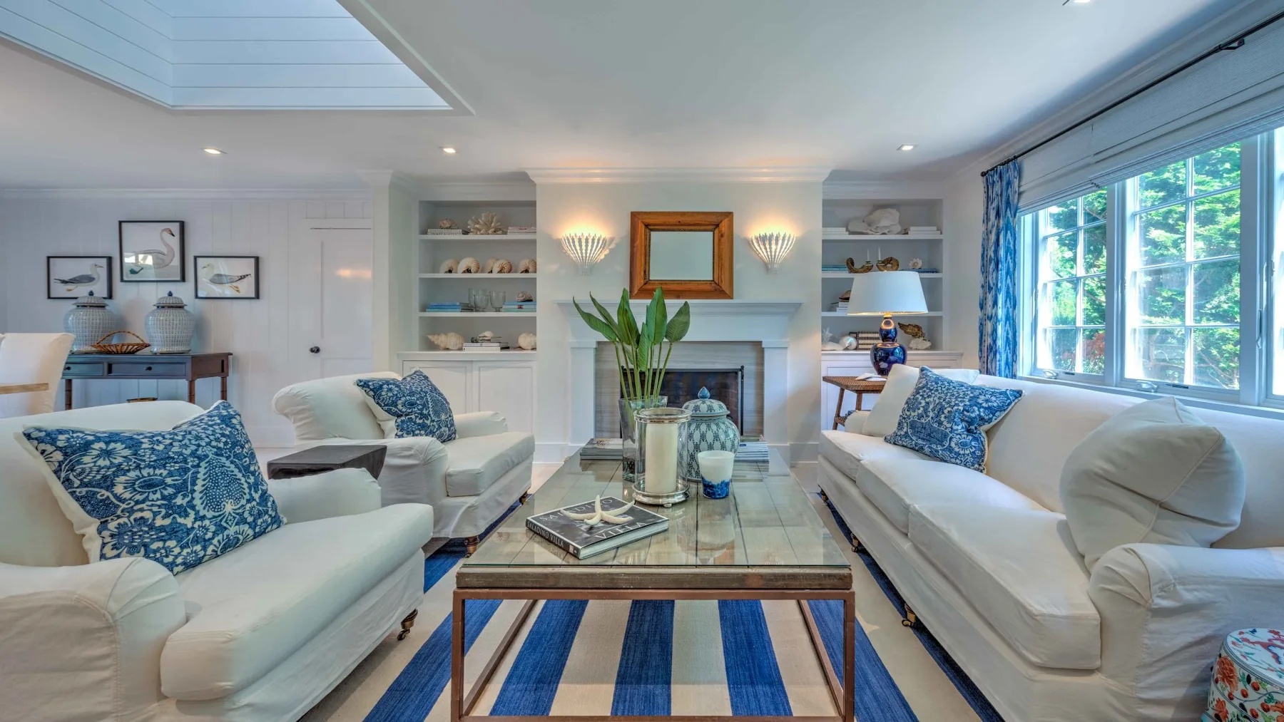 A bright living room with sofas arranged around a glass-topped coffee table.
