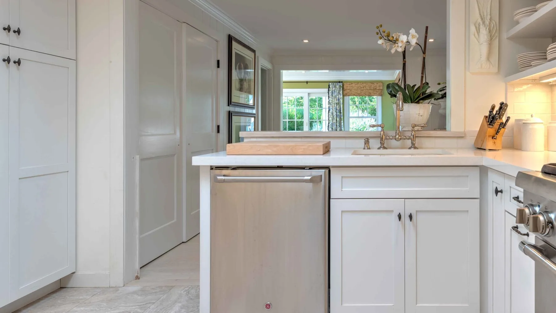A bright kitchen with a central island and a view into an adjoining room.