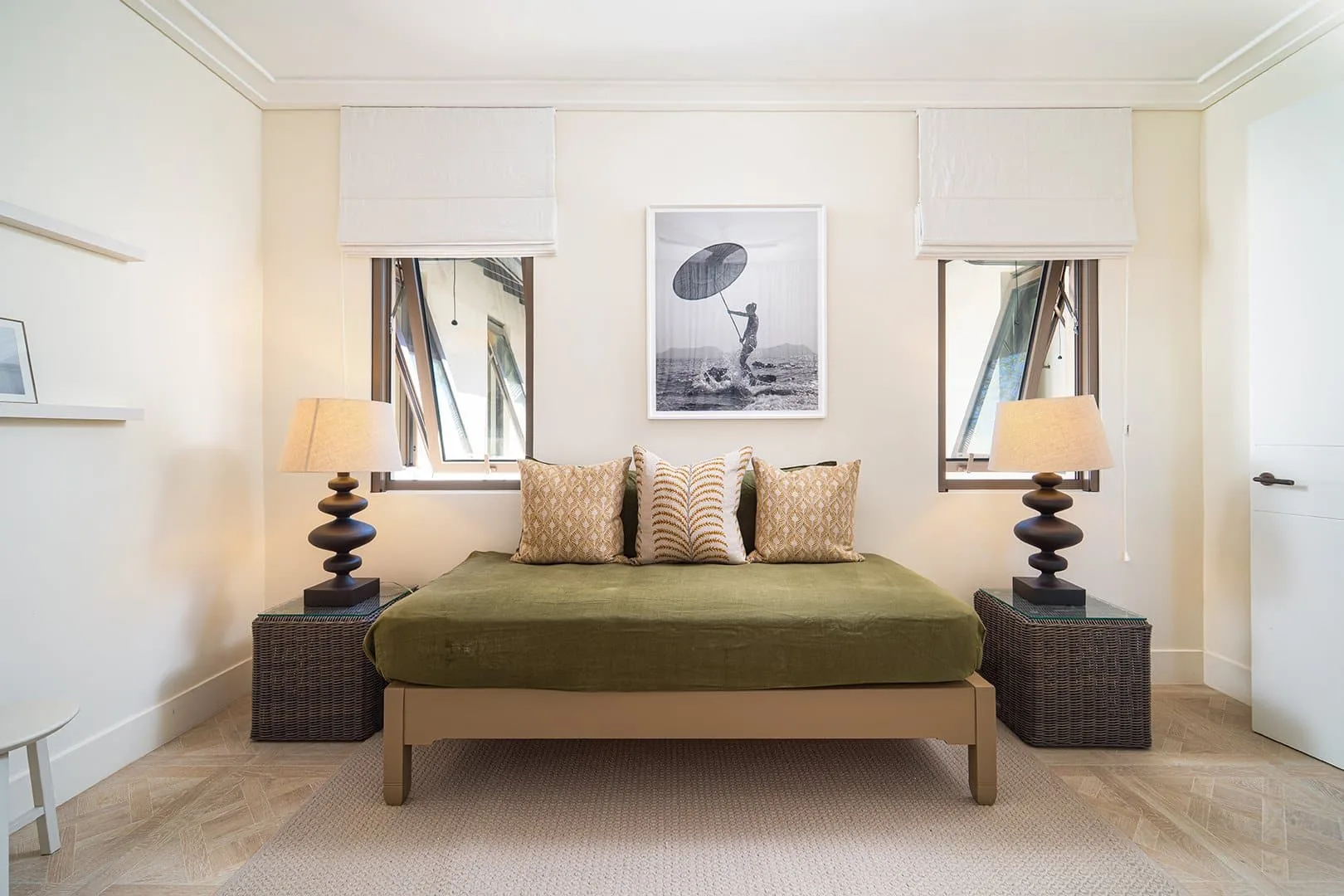 A bedroom with a bed dressed in green and patterned pillows.