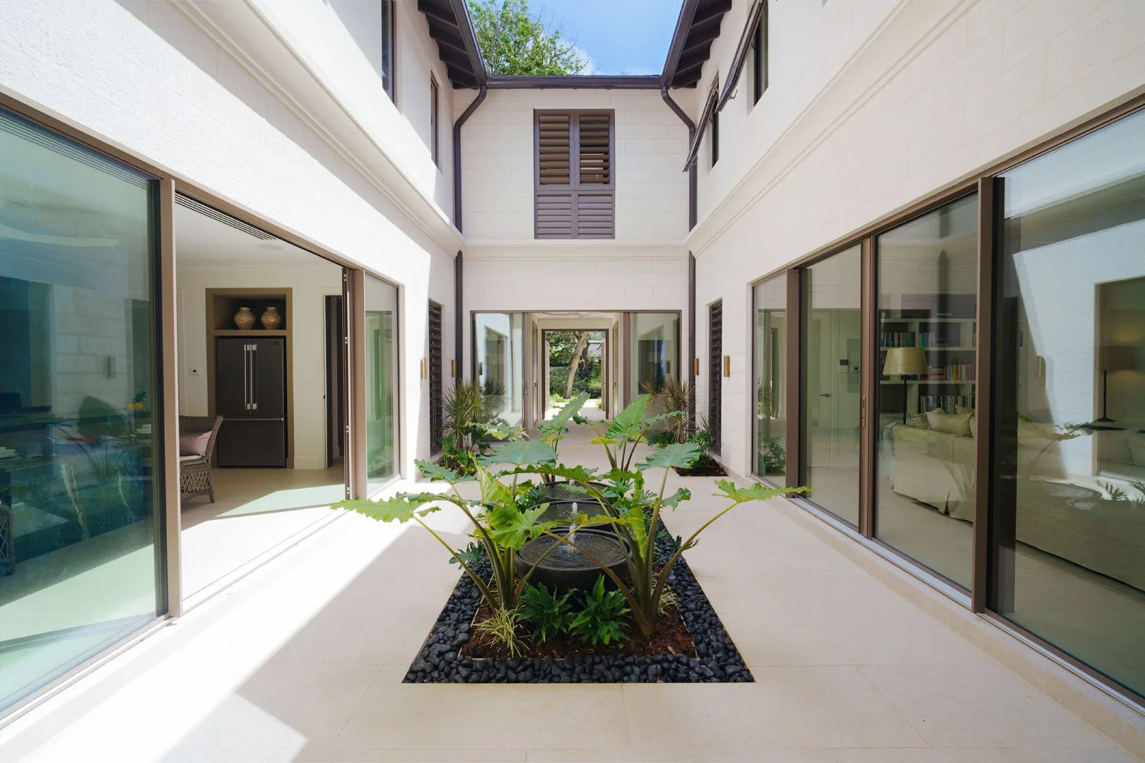 A bright indoor courtyard with a central planted bed and glass doors.
