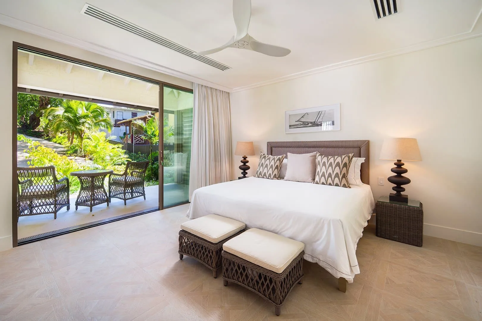 A bedroom with a large bed beside sliding glass doors opening onto a garden patio.