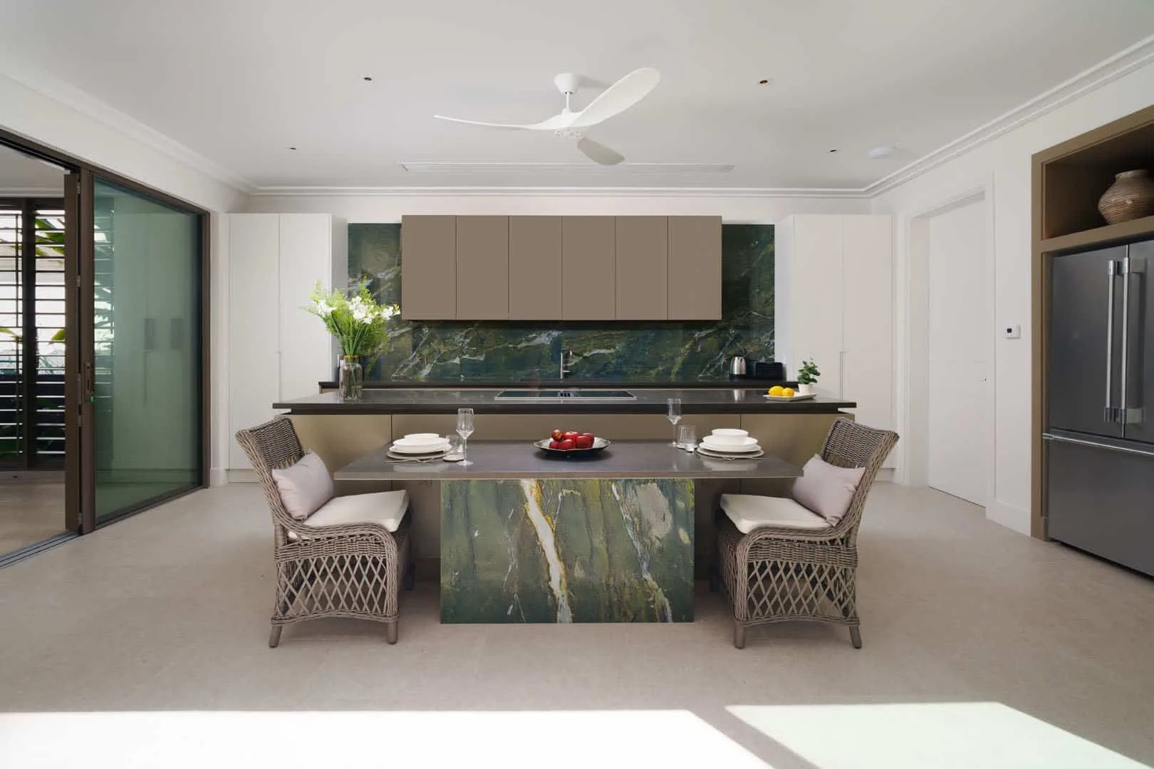 A modern dining area with a set table and kitchen cabinetry behind it.
