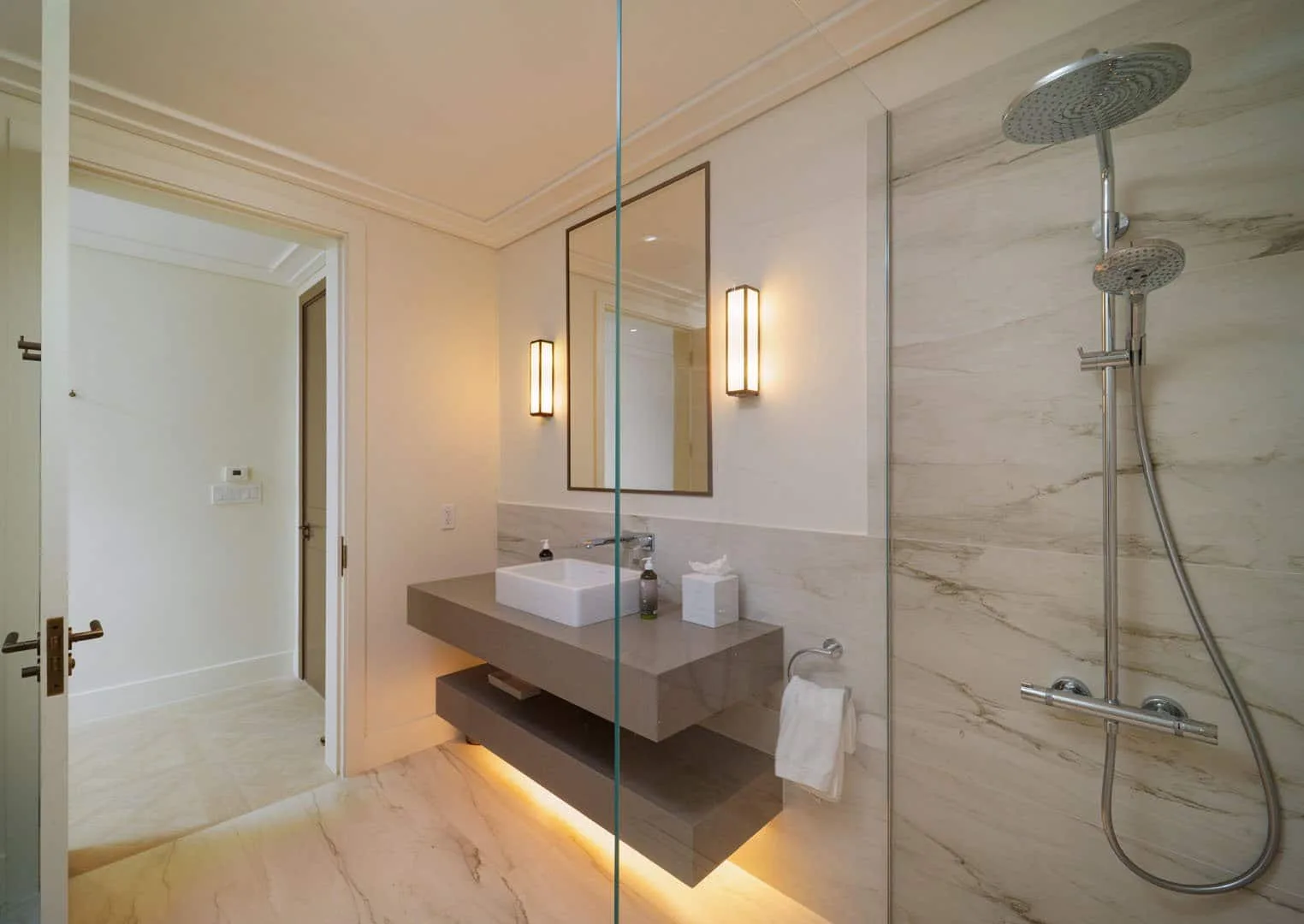 A bright bathroom with a floating vanity and a glass-enclosed shower.