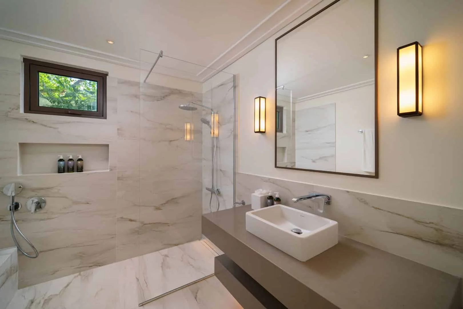 A bathroom with a glass shower and a vessel sink beneath a large mirror.