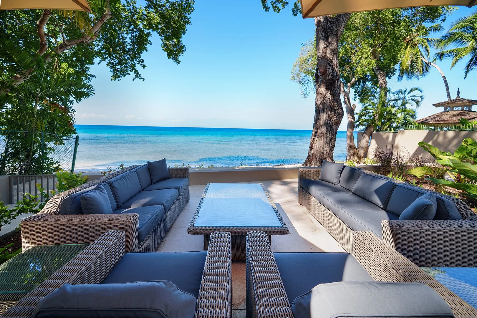 An outdoor seating area faces the ocean, with a low table between the sofas.