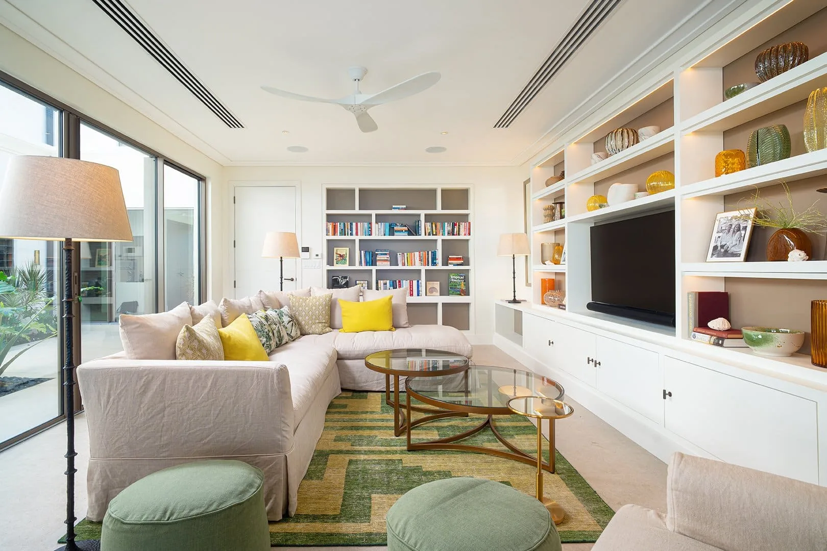 A bright living room with sectional seating, a television, and built-in shelves.