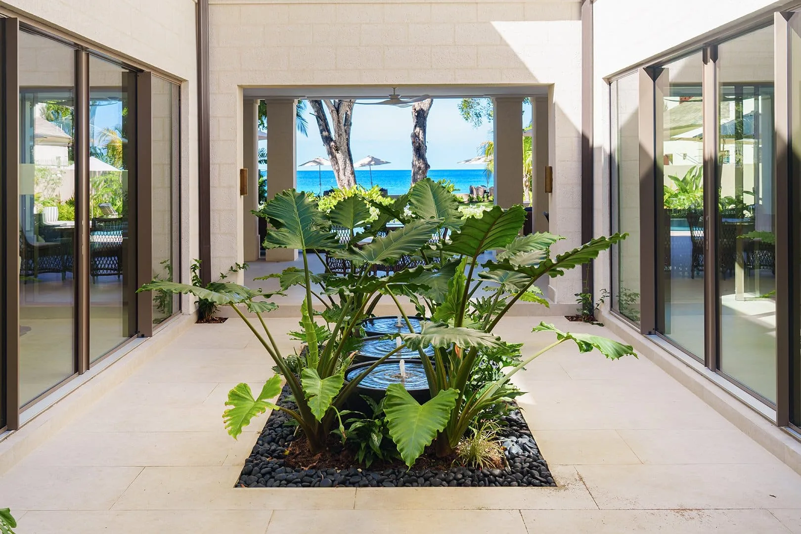 A bright courtyard with tropical plants and a view of the ocean.