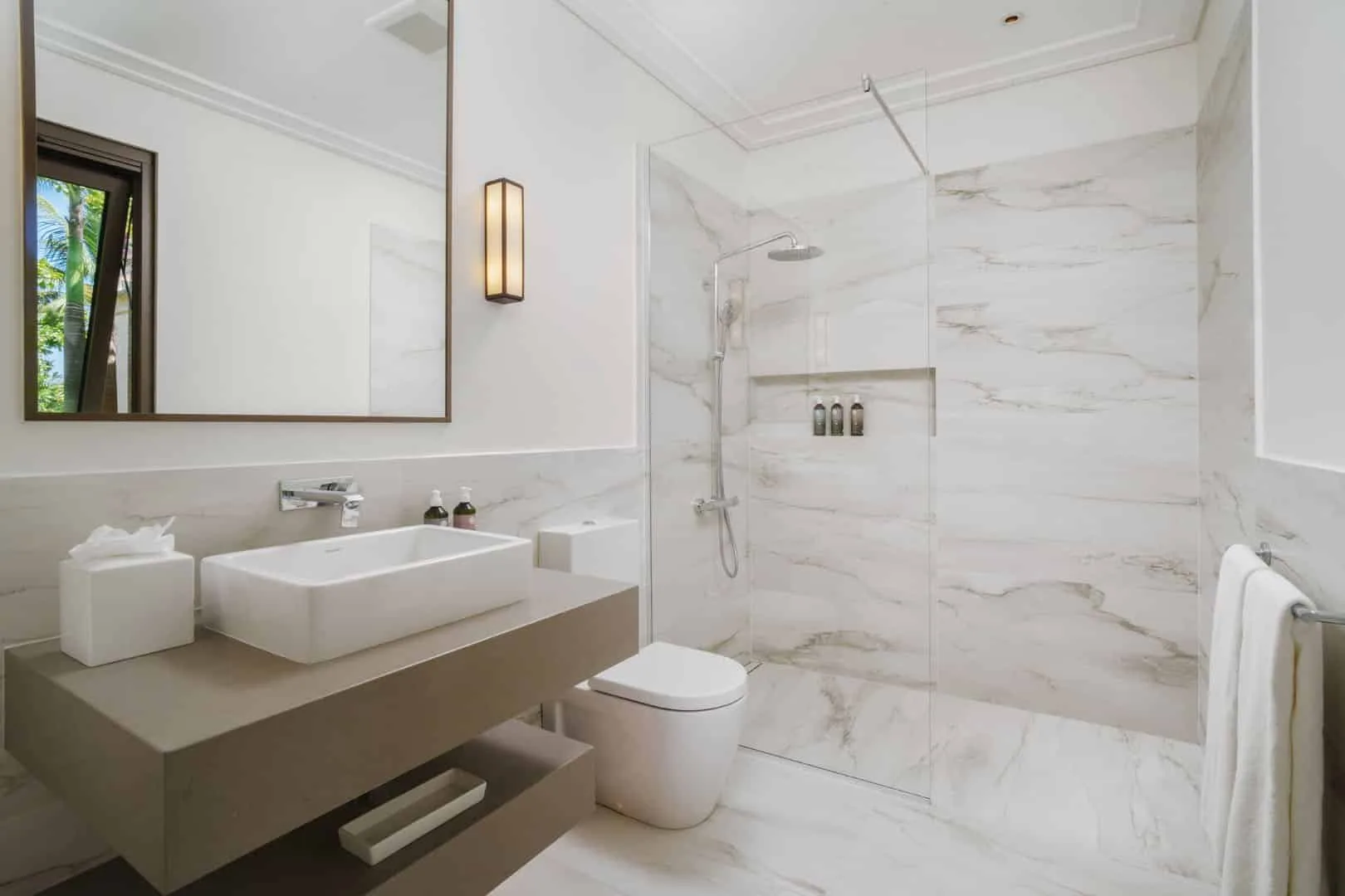 A bright bathroom with a sink, toilet, and glass shower.