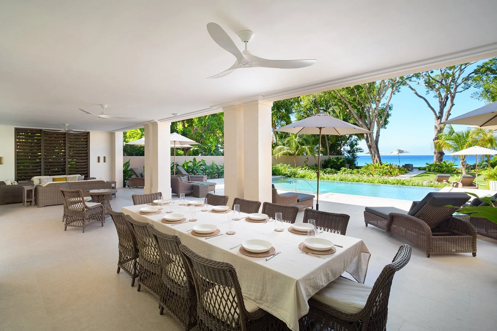 A covered outdoor dining area overlooks a swimming pool and garden.