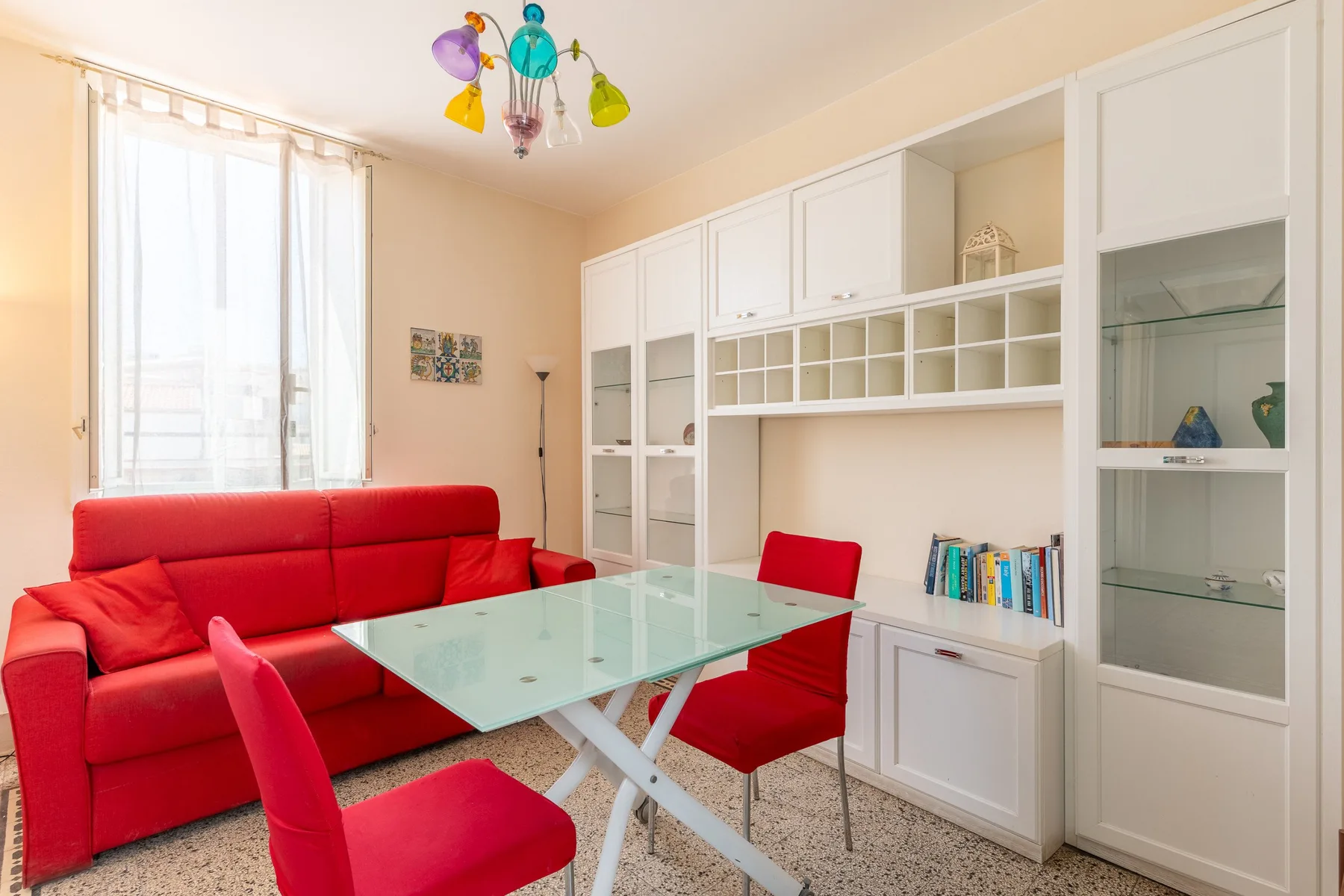 Una sala luminosa con asientos rojos, una mesa de vidrio y estanterías empotradas.