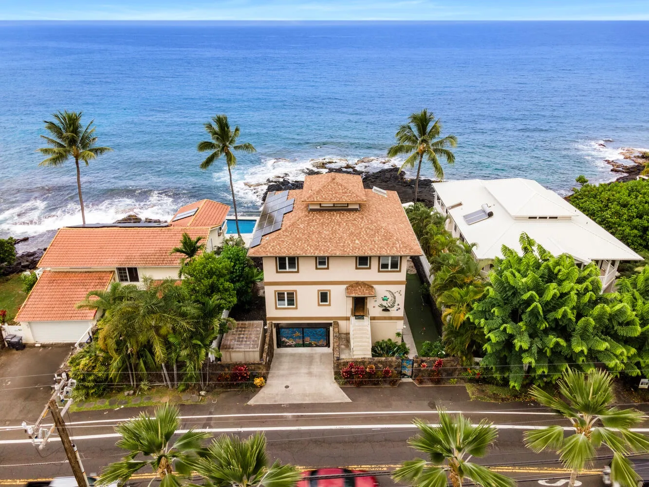 Vista aérea de casas junto al océano, con palmeras a lo largo de la costa.