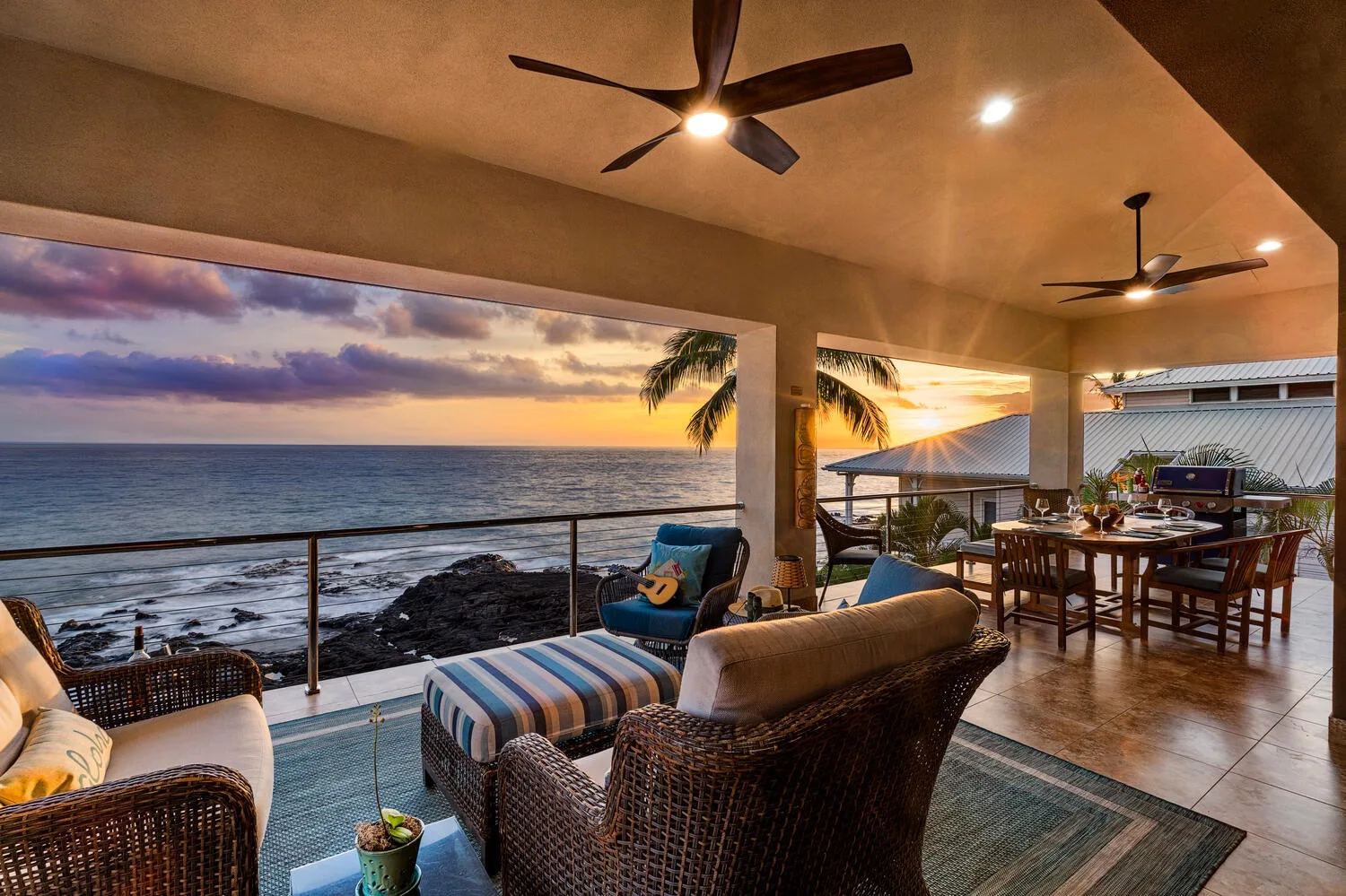 Un patio cubierto junto al mar, con asientos de mimbre y una mesa de comedor, da al océano.