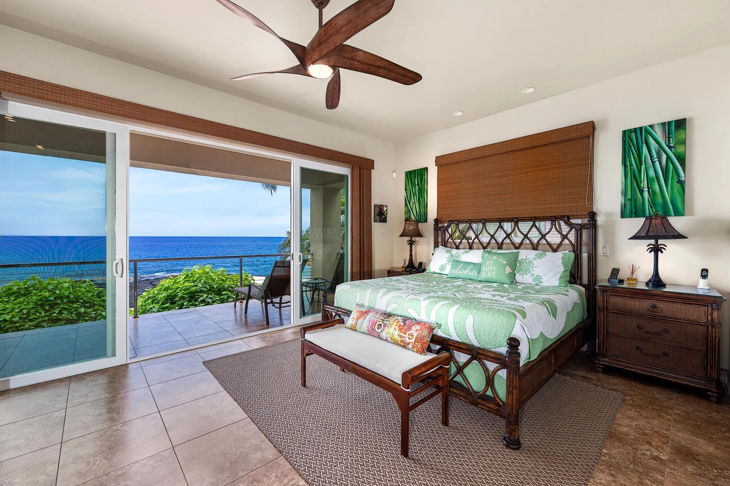 Un dormitorio con una cama verde y puertas corredizas de vidrio con vista al mar.