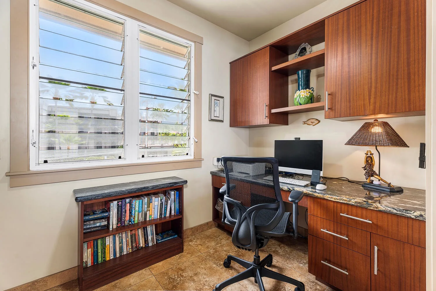 Un despacho en casa con escritorio, computadora y ventanas con vistas a la vegetación.
