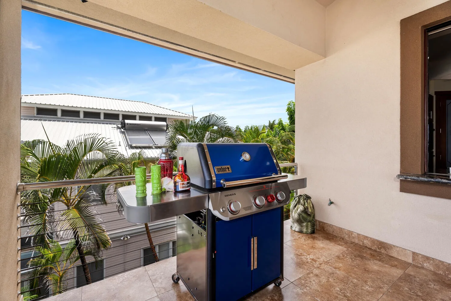 Una zona de cocina exterior cubierta con una parrilla azul junto a una amplia abertura.