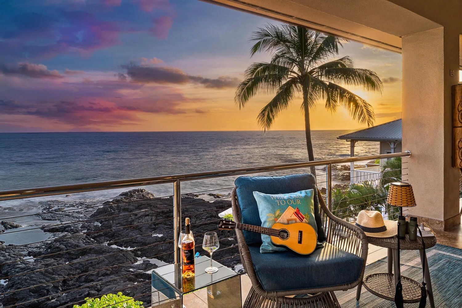 Una zona de estar en un balcón da al mar al atardecer, con una guitarra sobre una silla.