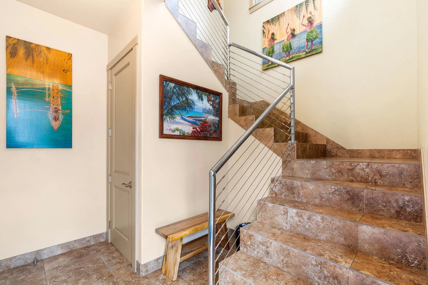 Una escalera interior con peldaños de piedra, barandillas metálicas y cuadros coloridos.